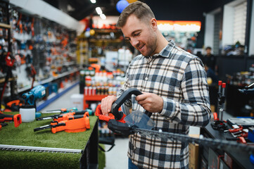 a man chooses a brushcutter in a hardware store