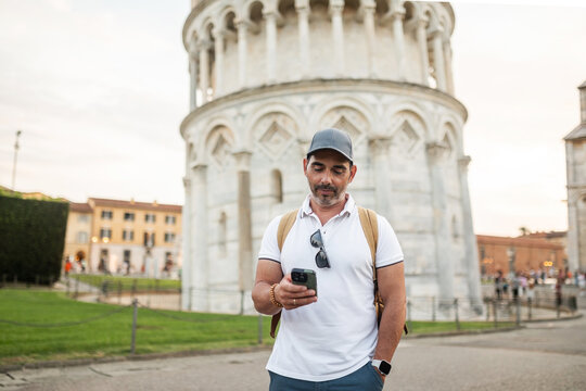 tourist using mobile phone next to the tower of pisa in italy