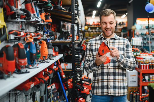 man choosing electric shears in gardening tools store