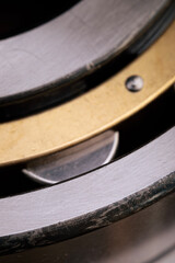 Close-up of a cylindrical roller bearing with brass cage and metallic rollers. Macro shot of industrial mechanical component. Engineering and machinery concept for design and print.