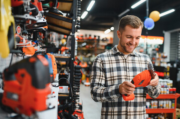 man choosing electric shears in gardening tools store