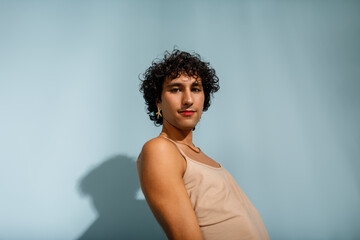 A young woman poses playfully against a  blue backdrop