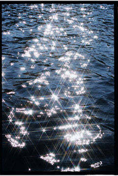 Sparkling sunlight reflection on serene water surface during daytime