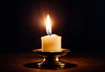 Candle flame glowing in dark setting on vintage holder
