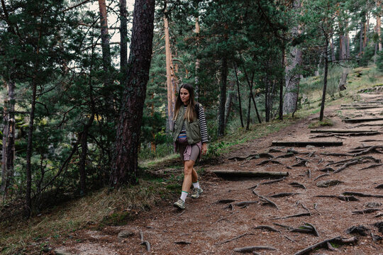 A professional female hiker takes off on a rugged path full of roots