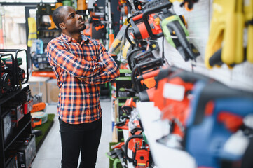A african american man chooses a power tool in a hardware store