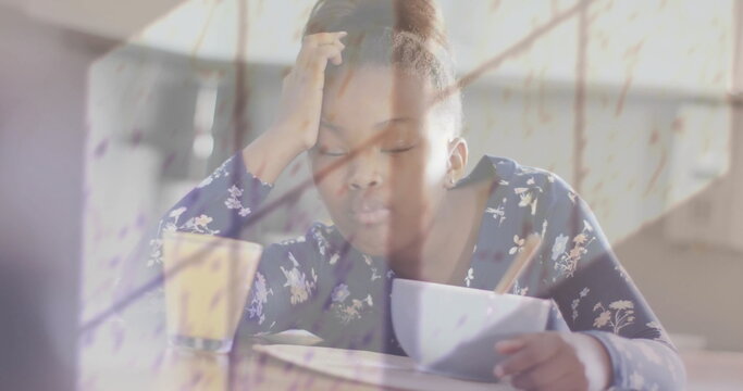 Image of shadow of window and rain over african american girl asleep at breakfast table