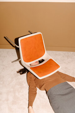 Conceptual Image of Woman with Chair Overhead on Floor
