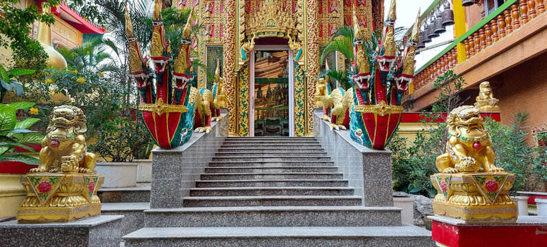 Majestic foo dogs guard the entrance to a vibrant thai temple, adorned with naga serpent sculptures