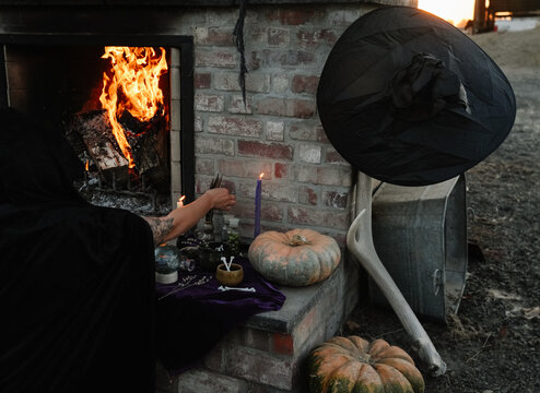 woman decorates outdoor fireplace for halloween