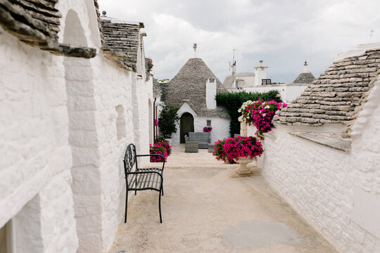 Alley adorned with flowers leading to the entrance of a Trulli house