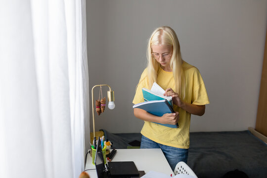 Student girl checks her workbooks in her room