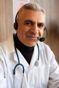 Doctor wearing headset and lab coat smiling 