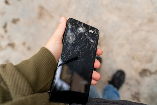 Hand Holding a Broken Smartphone Outdoors