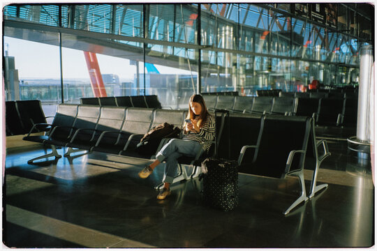 Film photo of female traveler sits on a bench at the New York airport