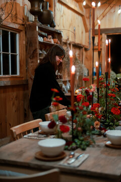 woman setting dinner table with red flowers in autumn