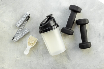 Sports nutrition - protein shaker and black dumbbells, top view