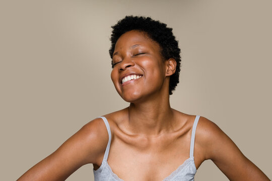 woman smiling with eyes closed on beige background - Powered by Adobe