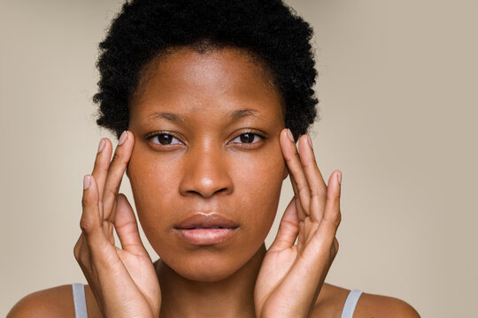 woman touching her face with a neutral expression