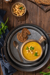 Pumpkin and chickpeas soup on brown rustic wooden background. Top view