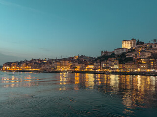 A serene sunset casts a warm glow over the Douro River, highlighting the historic architecture of Porto, Portugal.
