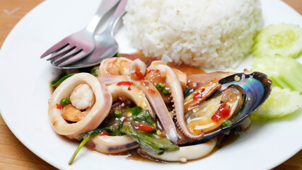 Savory Thai dish featuring spicy stir-fried seafood, including squid, shrimp and mussels, cooked with herbs and chili paste.