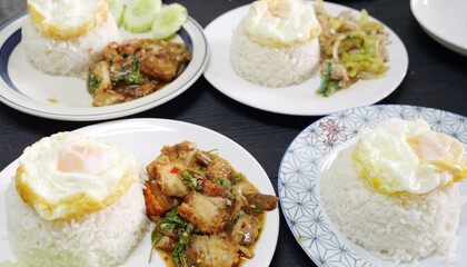 Variety of Thai basil stir-fry dishes served with steamed white rice and topped with fried eggs.