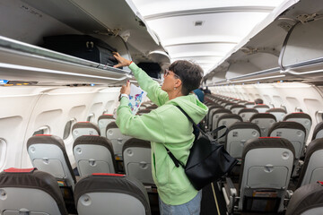 Woman placing luggage in overhead compartment on airplane