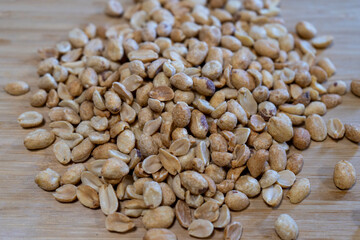 Peanuts spread out on a wooden board, highlighting their rustic and natural appeal.