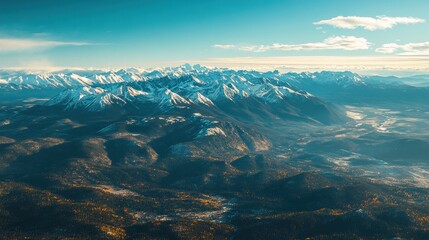 Aerial view of snow-capped mountains and valleys under a clear blue sky.