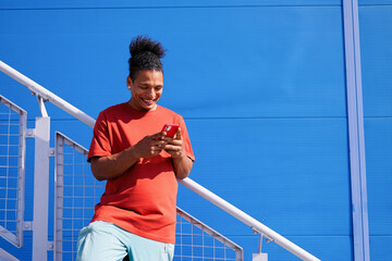 Happy Man Checking Phone Against Blue Wall