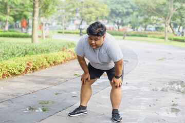 Exhausted Young Overweight Man Take a Break During Workout With Holding His Knee In The Park