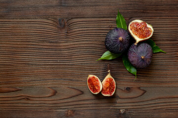 Whole and cut fresh ripe figs on wooden table. Top view