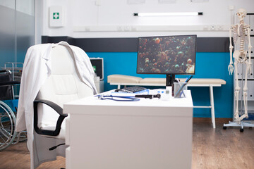 Vacant hospital room with computer displaying microscopic virus cells, symbolizing focus on...
