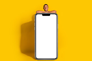 Full length photo of cheerful positive guy texting sms modern device empty space isolated yellow color background