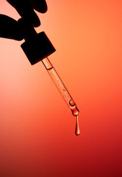 Hand holding dropper bottle with anti aging face serum.