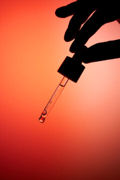 Hand holding dropper bottle with anti aging face serum.