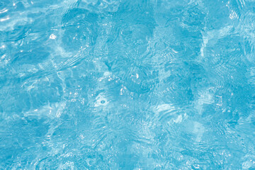Blue water with ripples on the surface. Defocus blurred transparent blue colored clear calm water surface texture with splashes and bubbles. Water waves with shining pattern texture background.