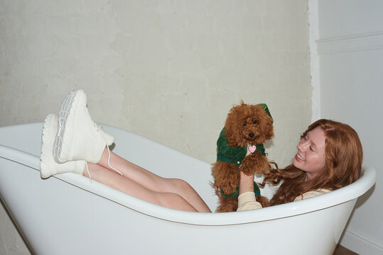 Teen lying in a bathtub with her dog 