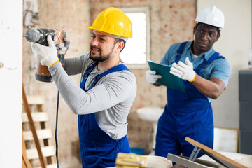 Head of construction checks how the builder works with a puncher