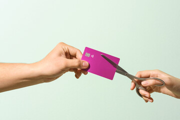 Hands Cutting Credit Card with Scissors on Green Background