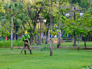 A janitor is cutting grass with a machine