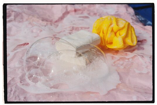 Two bars of soap with a loofah in the lather 