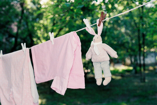 Close-up hanging washed baby clothing and rabbit toy on the street.