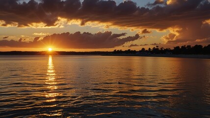 Naklejka premium Fiery sunset over calm lake with dark clouds.