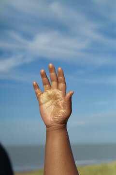 A golden 
hand reaching for the sky at the beach
