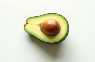 A single ripe avocado, halved to reveal the seed, on a plain white background