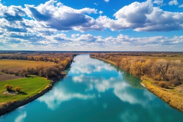 Obraz premium Aerial view of a river reflecting clouds in autumn.