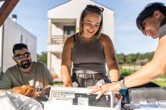 Friends preparing portable fridge for summer vacation lunch