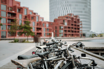 A row of parked bicycles with modern buildings in the background
